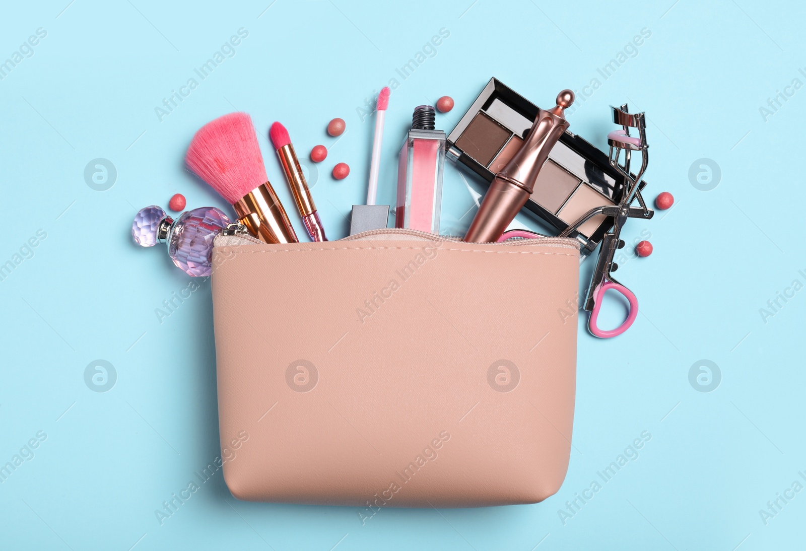 Photo of Cosmetic bag and makeup products with accessories on light blue background, flat lay