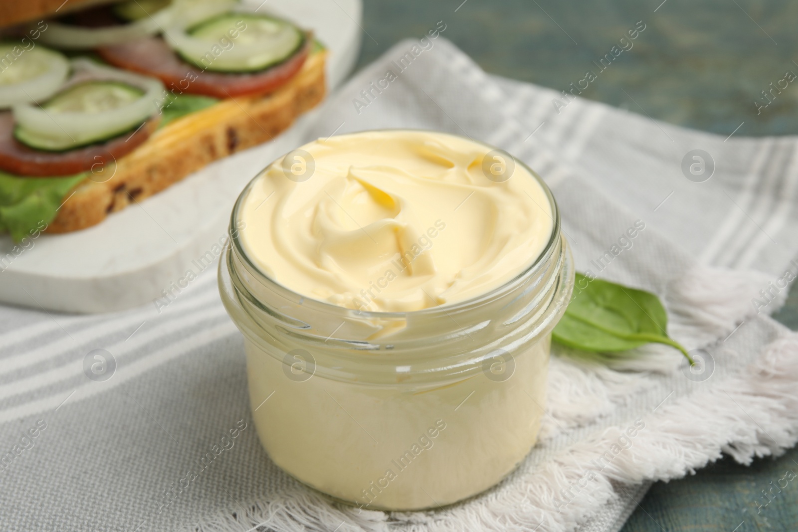 Photo of Jar of delicious mayonnaise and napkin on light blue wooden table