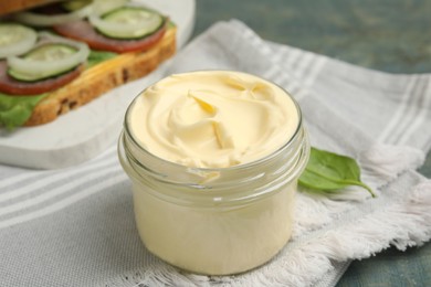 Jar of delicious mayonnaise and napkin on light blue wooden table