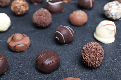 Photo of Different tasty chocolate candies on black table