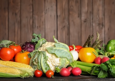 Photo of Assortment of fresh vegetables on table against wooden background. Space for text