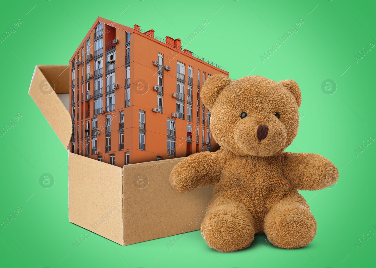 Image of Cute toy bear near cardboard box with building on green background