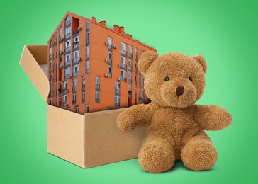 Image of Cute toy bear near cardboard box with building on green background