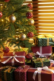 Photo of Pile of gift boxes near decorated Christmas tree indoors