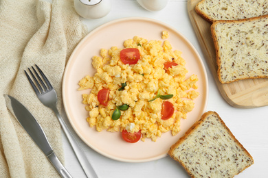 Photo of Tasty scrambled eggs served on white wooden table, flat lay