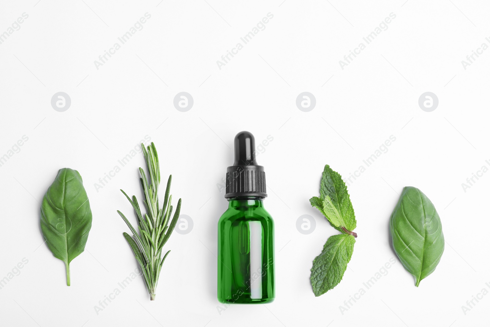 Photo of Little bottle of essential oil with different herbs on white background, top view