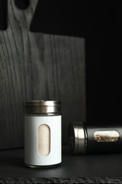 Photo of Salt and pepper shakers on black table