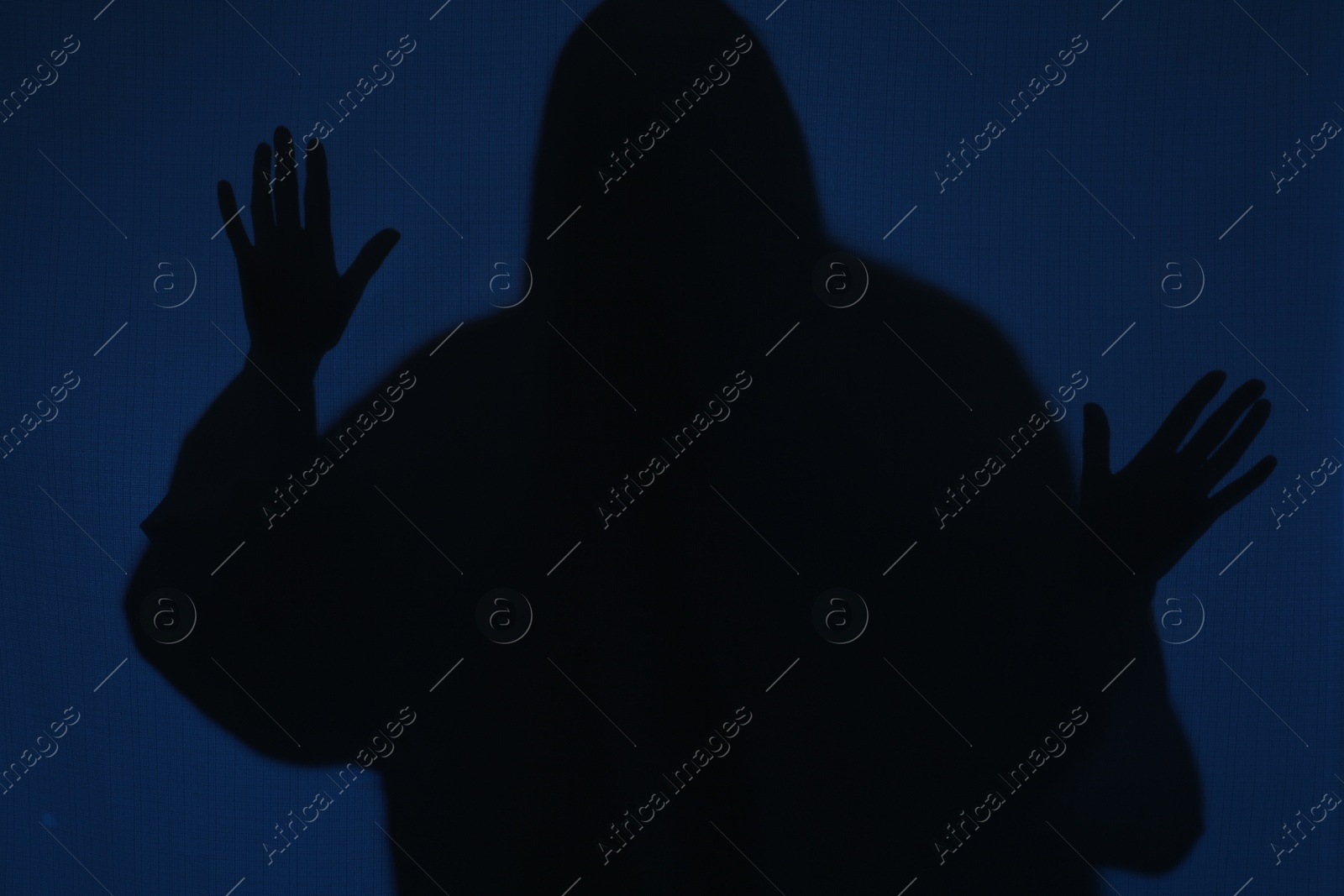 Photo of Silhouette of creepy ghost behind dark blue cloth