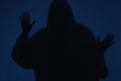 Photo of Silhouette of creepy ghost behind dark blue cloth