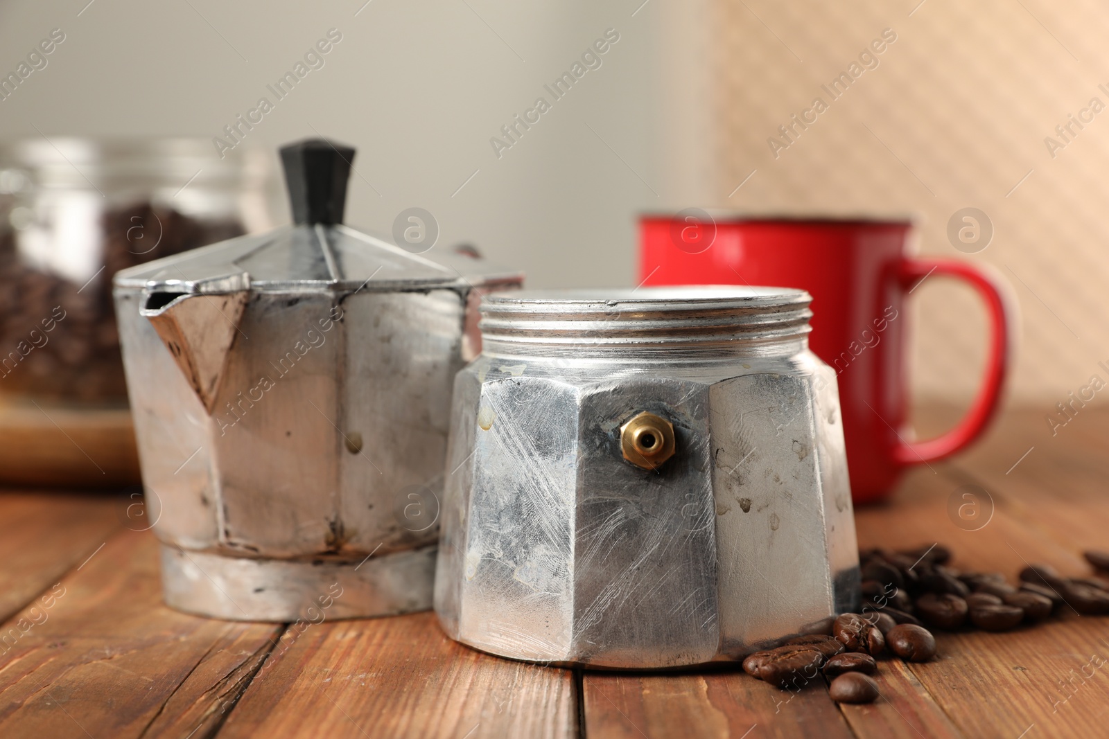 Photo of Moka pot and coffee beans on wooden table indoors, closeup