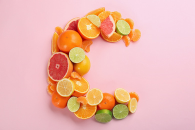 Photo of Letter C made with citrus fruits on pink background as vitamin representation, flat lay