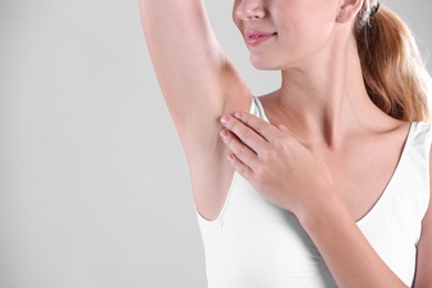 Photo of Young woman showing armpit on grey background, space for text. Using deodorant