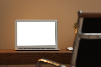 Photo of Laptop with blank screen on table indoors. Space for text