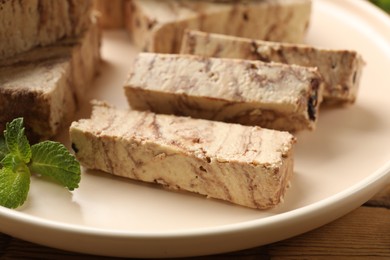 Photo of Tasty chocolate halva with mint on wooden table, closeup