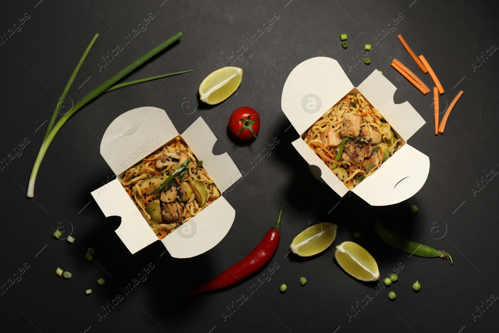 Photo of Boxes of wok noodles with vegetables and meat on black background, flat lay