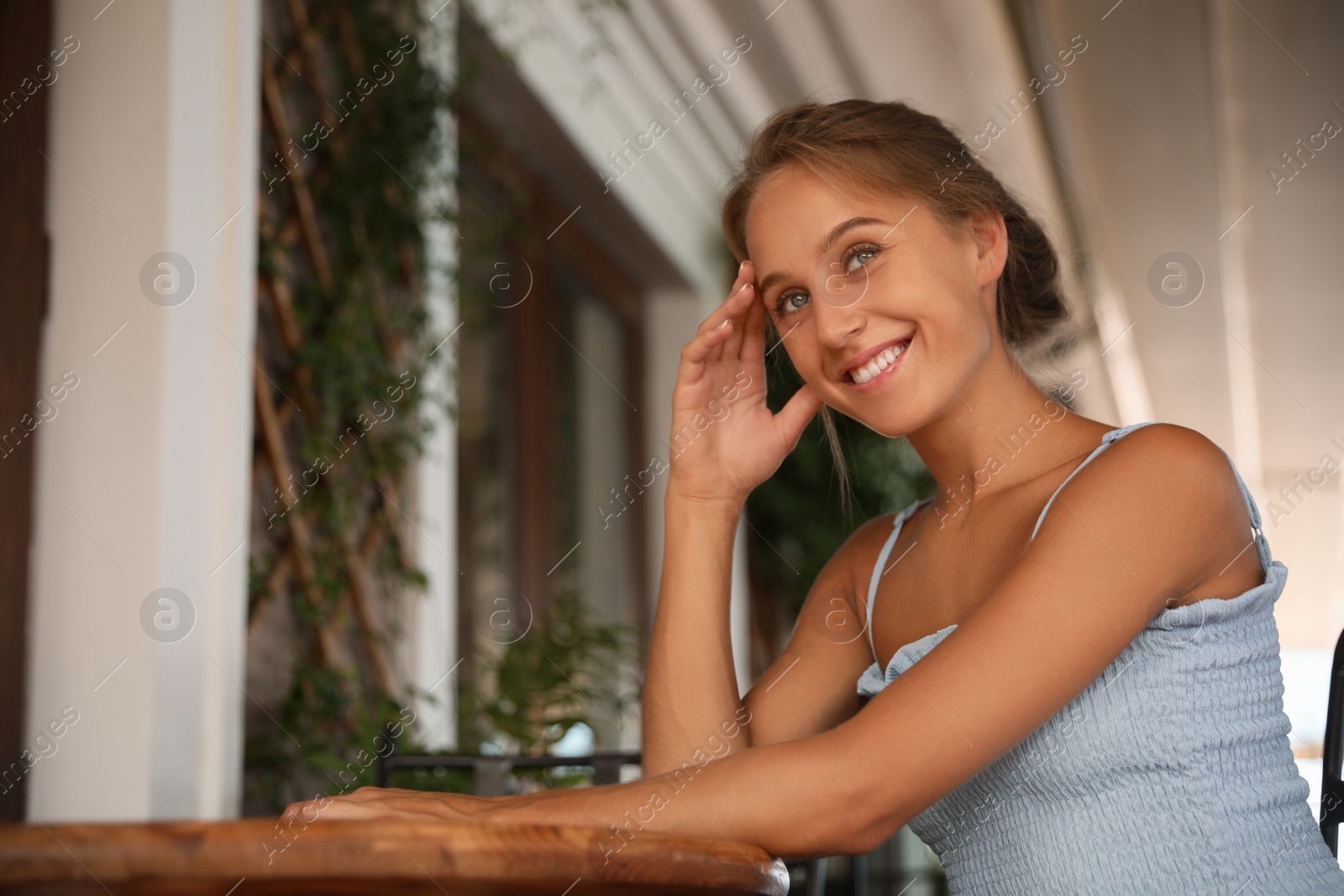 Photo of Beautiful young woman sitting on indoor terrace in cafe, space for text