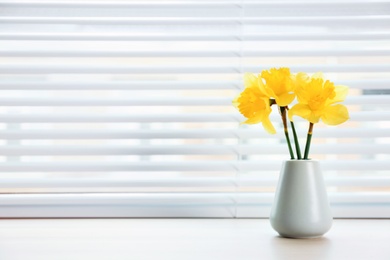 Photo of Window with blinds and beautiful bouquet on sill, space for text