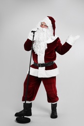Santa Claus singing with microphone on light grey background. Christmas music