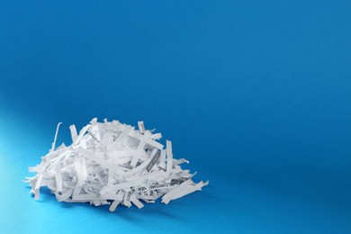 Heap of shredded paper strips on light blue background, space for text