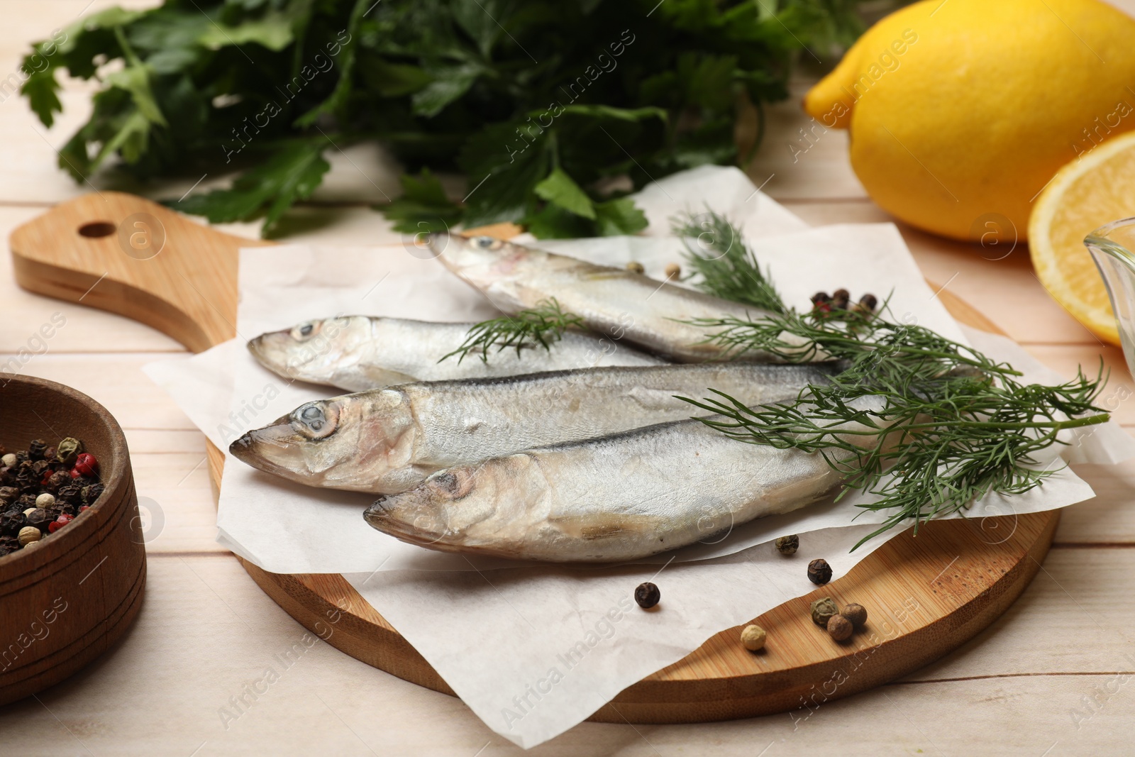 Photo of Fresh raw sprats, peppercorns and dill on light wooden table, closeup