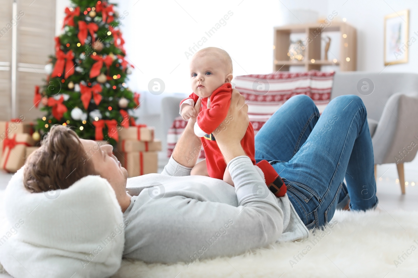 Photo of Young man with baby in Christmas suit at home