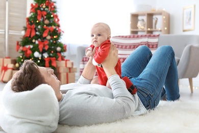 Young man with baby in Christmas suit at home