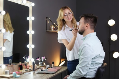 Professional makeup artist working with client in dressing room