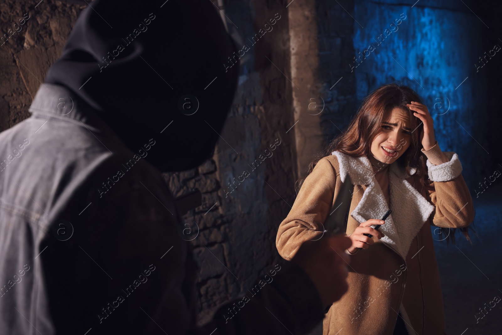 Photo of Criminal threatening young woman with knife in alley at night. Self defense concept