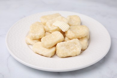Plate of tasty lazy dumplings with butter on white marble table