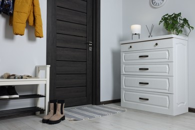 Shoe storage bench and chest of drawers near white wall in hallway. Interior design