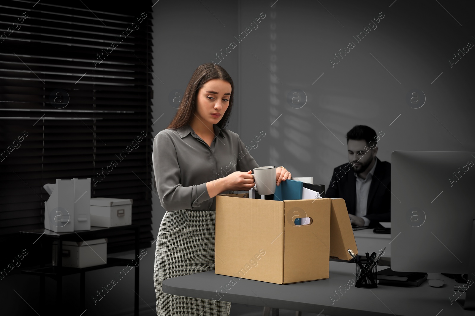 Image of Dismissed woman packing personal stuff into box in office