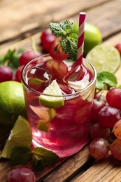 Photo of Soda water with grapes, ice, lime and mint on wooden table. Refreshing drink