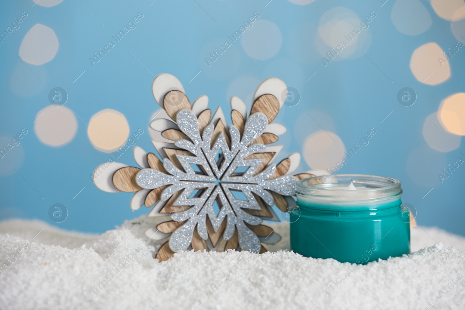 Photo of Jar of hand cream and decorative snowflake on snow against blurred lights. Winter skin care