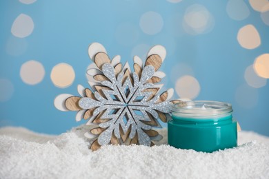 Jar of hand cream and decorative snowflake on snow against blurred lights. Winter skin care