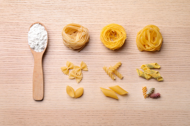 Photo of Flat lay composition with different types of pasta on wooden table