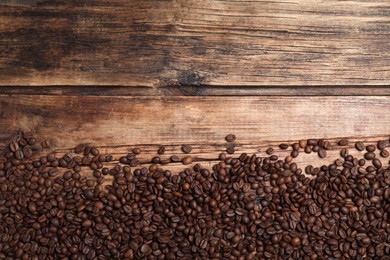 Many roasted coffee beans on wooden table, flat lay. Space for text