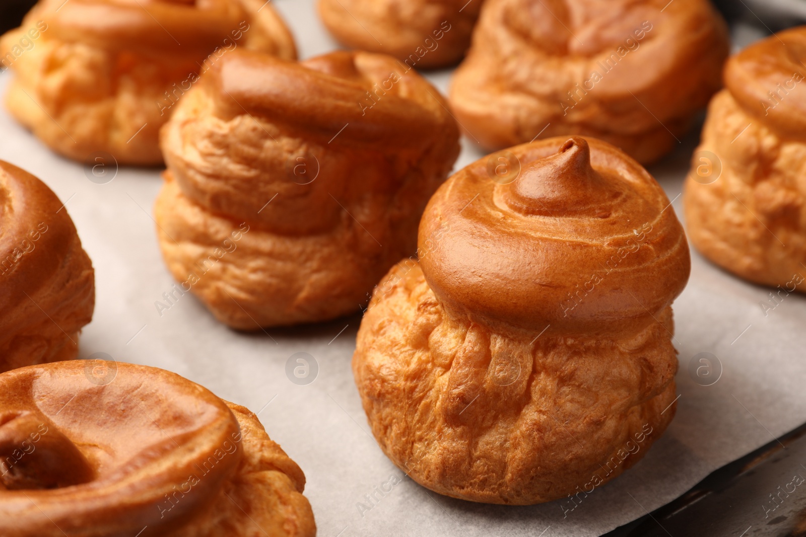 Photo of Delicious fresh profiteroles on baking pan, closeup