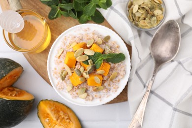 Photo of Tasty wheat porridge with pumpkin and mint in bowl served on table, flat lay