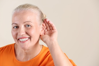 Photo of Mature woman with hearing problem on light background. Space for text