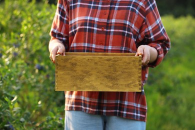 Woman holding wooden box outdoors, closeup view