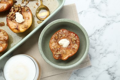 Photo of Tasty baked quinces with nuts and cream cheese served on white marble table, flat lay
