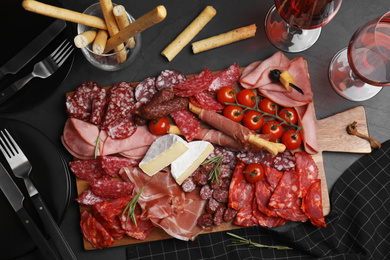 Tasty ham with other delicacies served on black table, flat lay