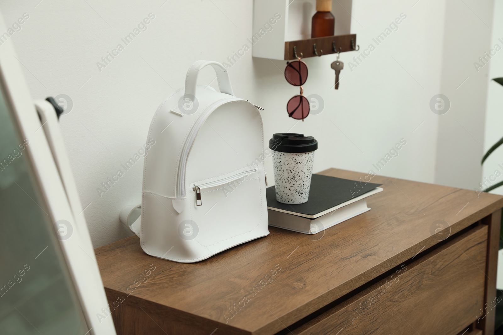 Photo of Stylish urban backpack on wooden chest of drawers in hallway