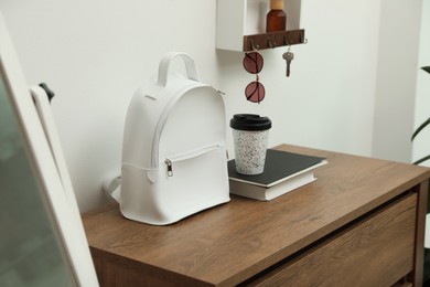 Stylish urban backpack on wooden chest of drawers in hallway