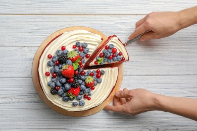 Photo of Woman taking piece of delicious homemade red velvet cake from table, top view