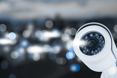 Modern security CCTV camera against blurred background, space for text