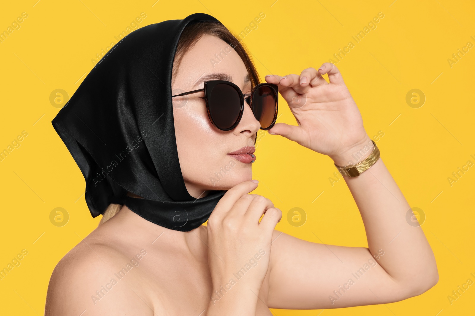 Photo of Young woman with lip piercing and sunglasses on yellow background