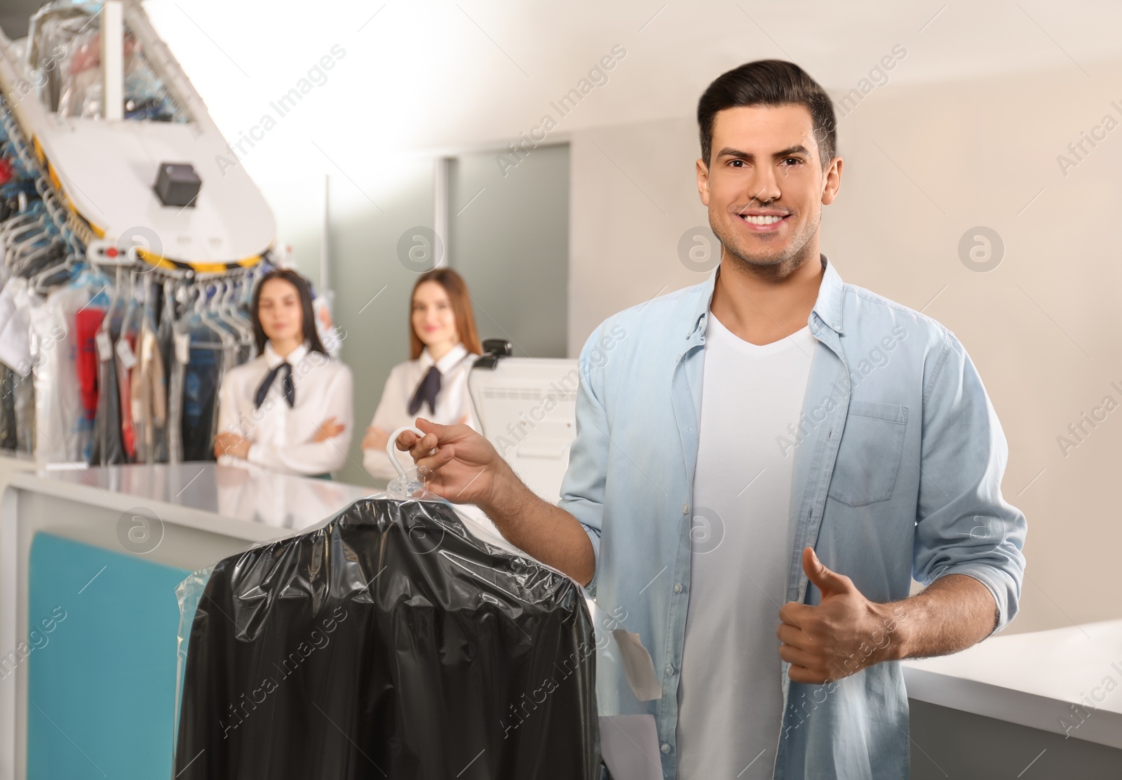 Photo of Happy client with clothes at modern dry-cleaner's