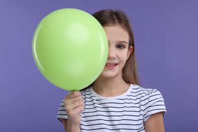 Happy girl with green balloon on violet background