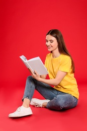 Photo of Young woman reading book on color background, space for text